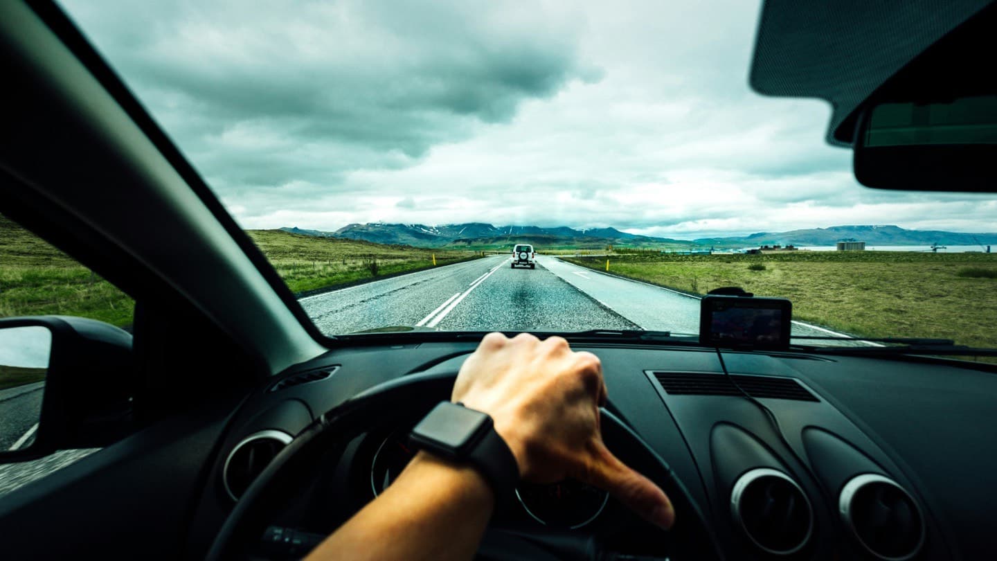 Driver's view through the windscreen of a car on an open highway with mountains ahead, the kind of long-haul driving a reliable used car is bought for